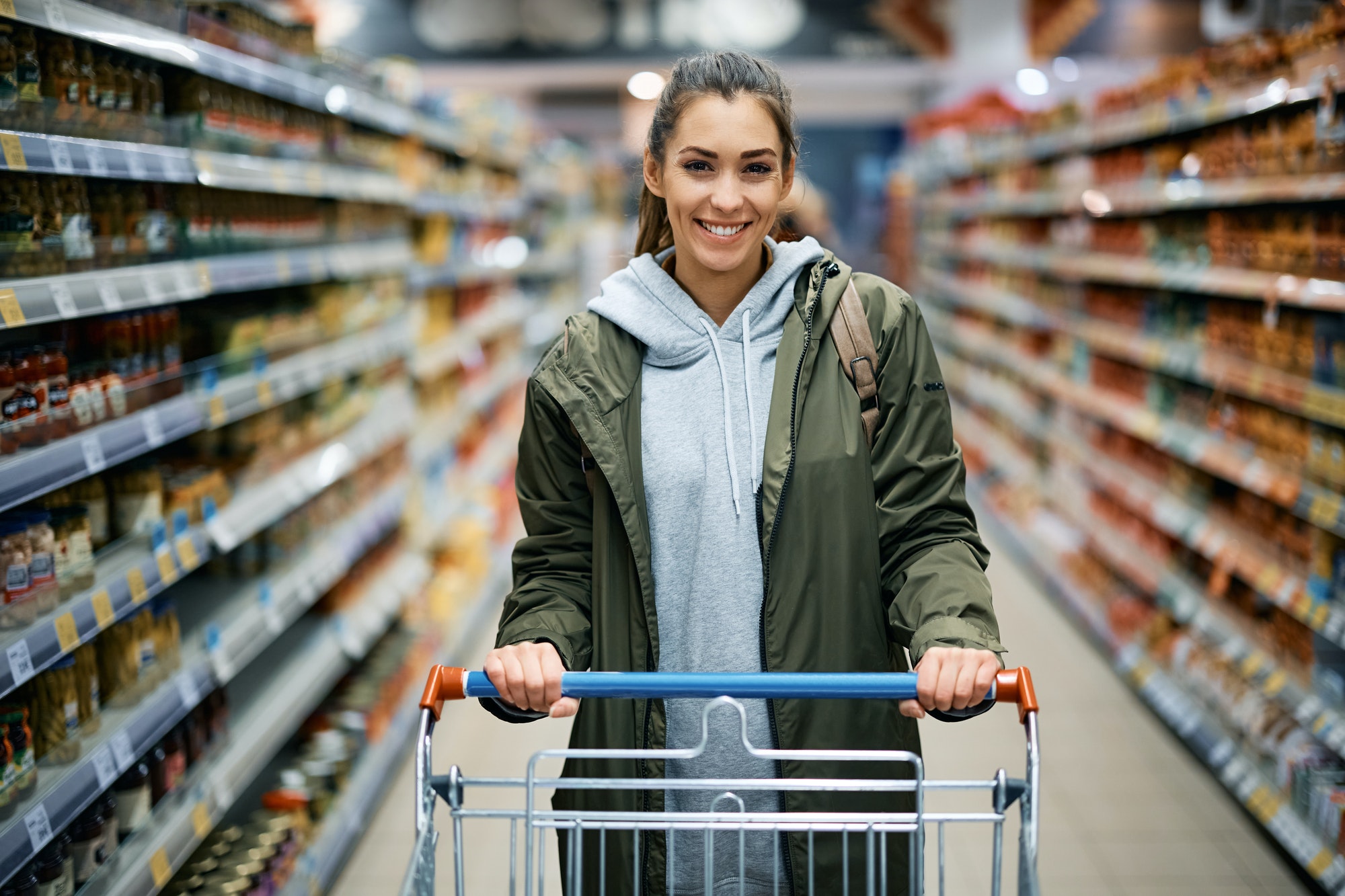 Happy woman shopping in supermarket and looking at camera.